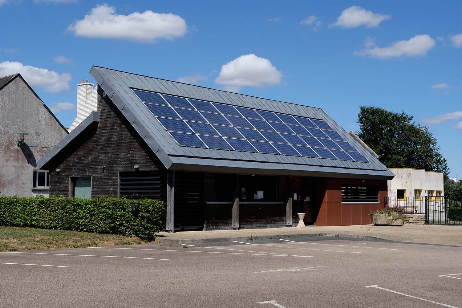 Bureaux en béton, partiellement recouvert de bois, équipé de panneaux solaires